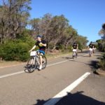 A group of people riding bikes on a road while participating in a small business marketing workshop.