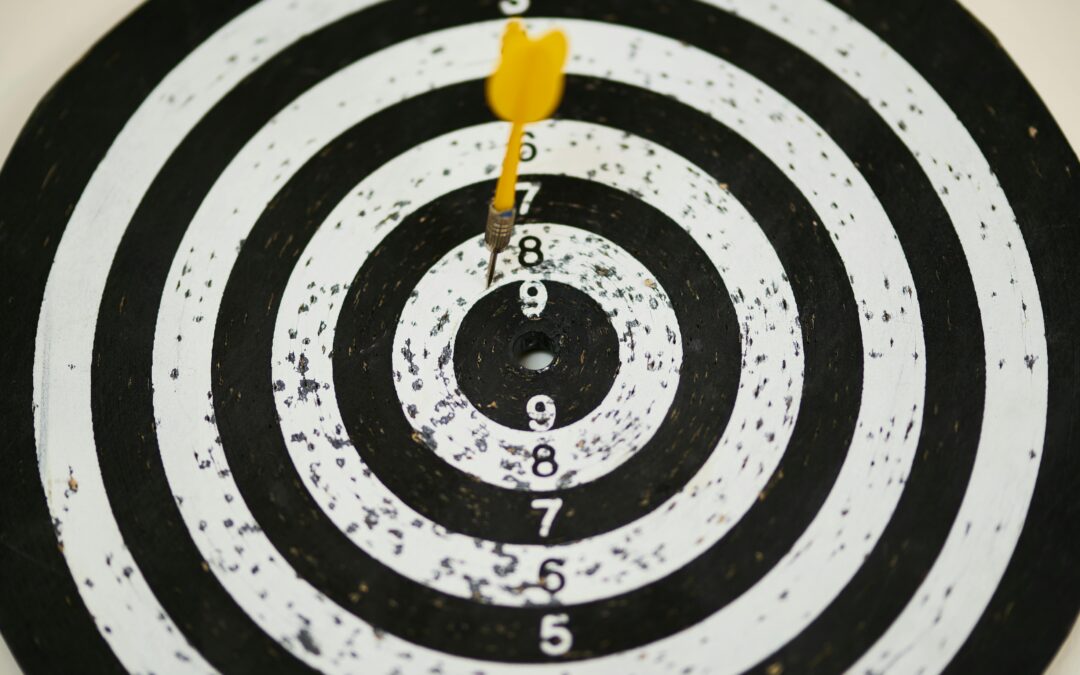 A dart board with a yellow dart sticking in the bullseye. The board shows signs of extensive use with many marks and holes around the target area, resembling the precision needed for successful Meta Ads audience targeting.